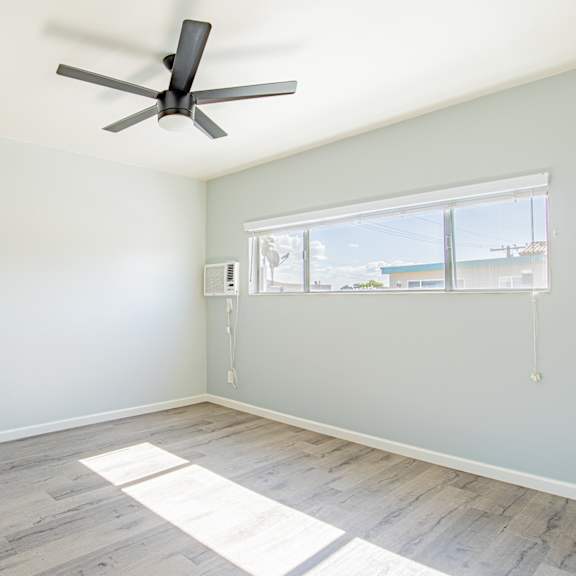 an empty room with a ceiling fan and a window