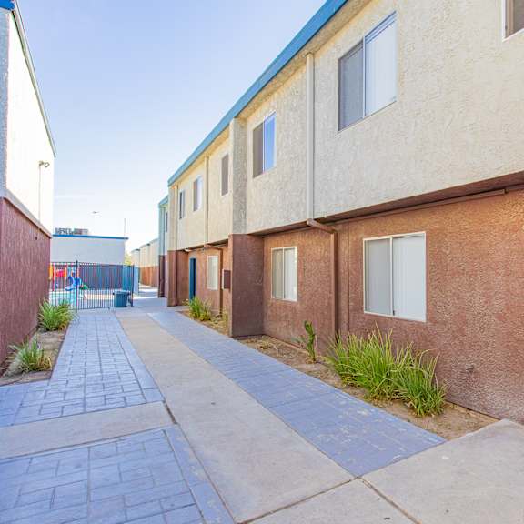 an empty sidewalk in front of a building with blue doors