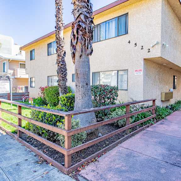 an apartment building with a sidewalk and palm trees