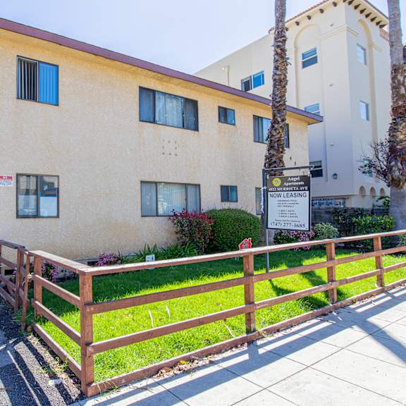 an apartment building with a fence and a sidewalk in front of it