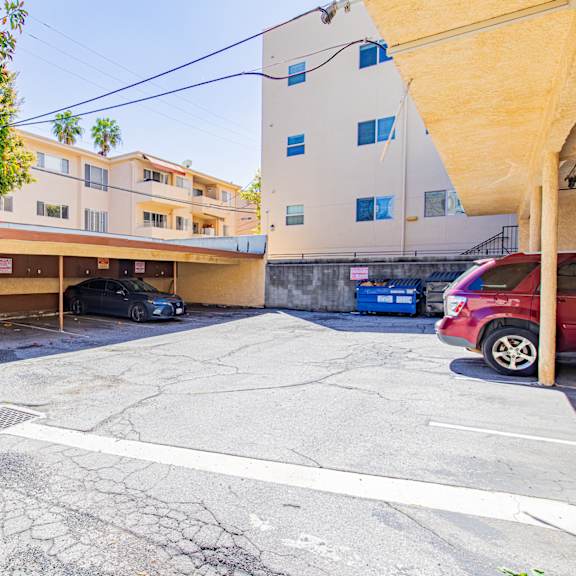 a parking lot with a building and a red car in front of it