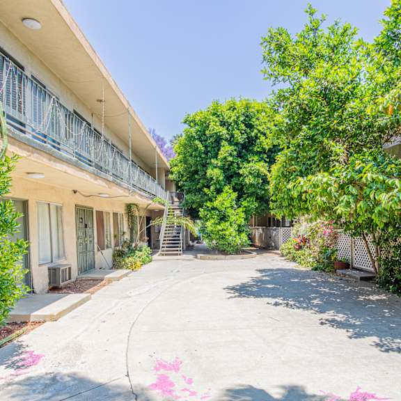 an empty sidewalk next to a building with trees