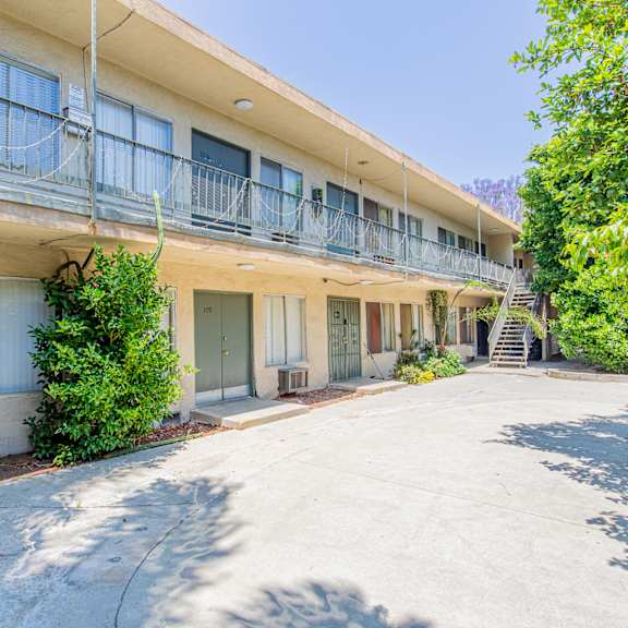 the courtyard of an apartment building with balconies and a driveway