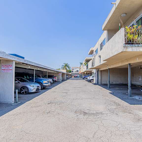 the entrance to the parking lot of a building with cars parked on both sides