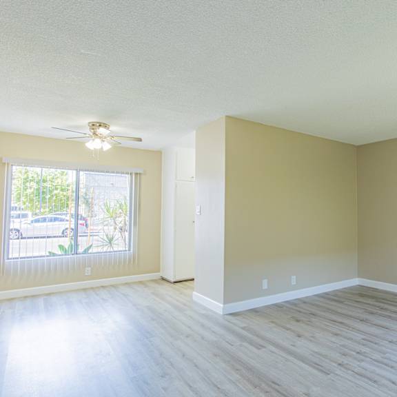 an empty living room with wood floors and a ceiling fan