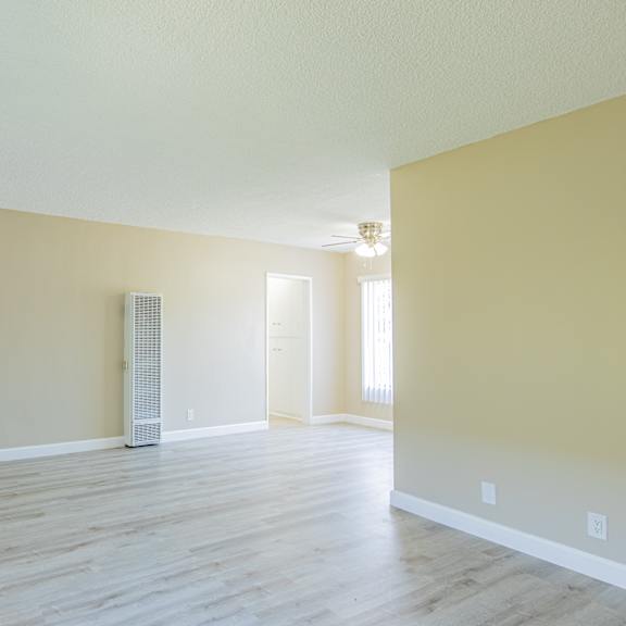 an empty living room with a hard wood floor and yellow walls