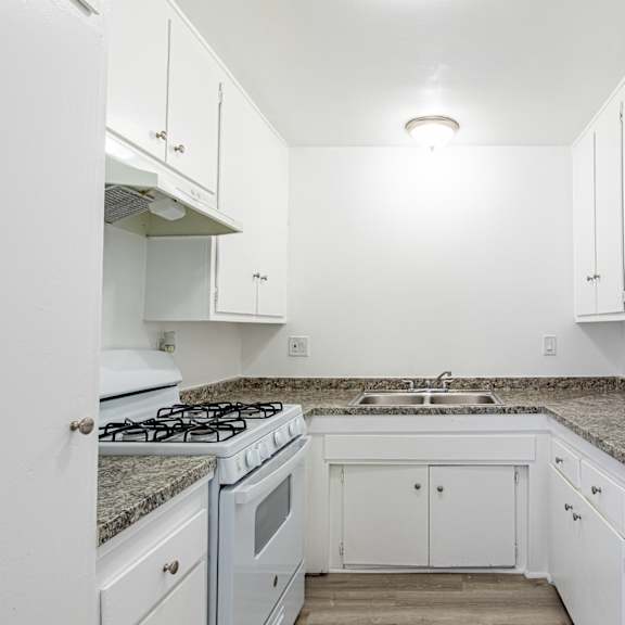 an empty kitchen with white cabinets and granite counter tops