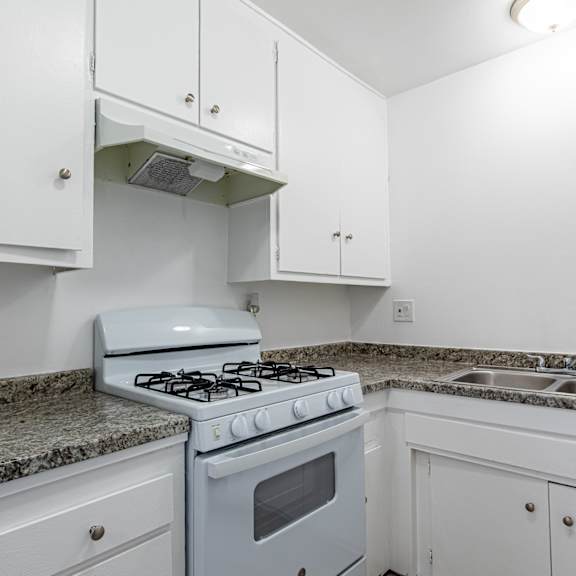 a kitchen with white appliances and granite counter tops and white cabinets