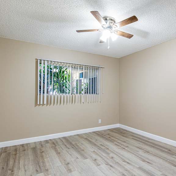 an empty living room with a ceiling fan and a window