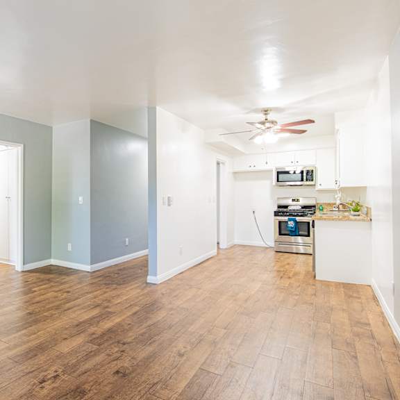 a room with a ceiling fan and a kitchenette in the corner.