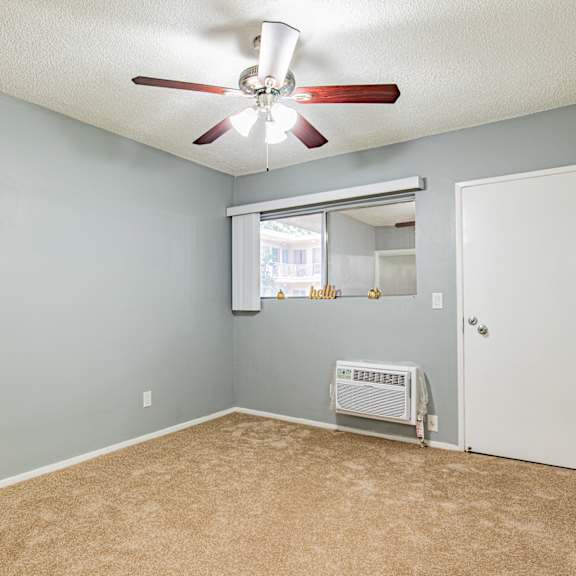 a room with a ceiling fan and a window with blinds.
