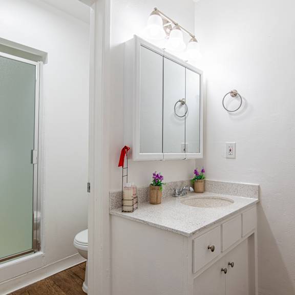 a white bathroom with a sink and mirror.
