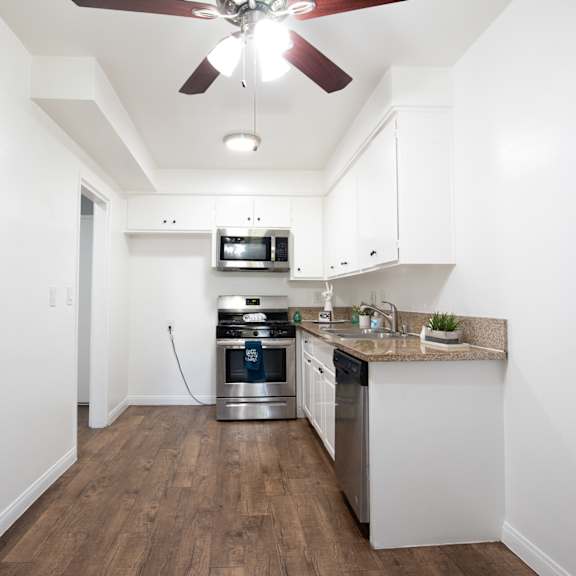 a kitchen with a fan on the ceiling and a stainless steel oven.