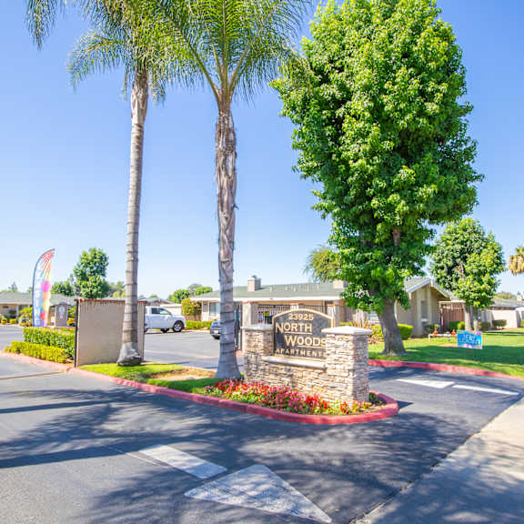 a street with a sign and palm trees in front of a building