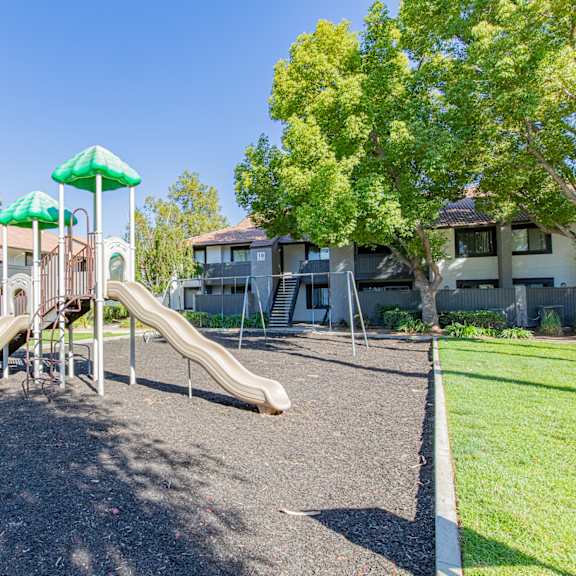 a playground with a green umbrella and a slide at metro 3610, riverside, 92505