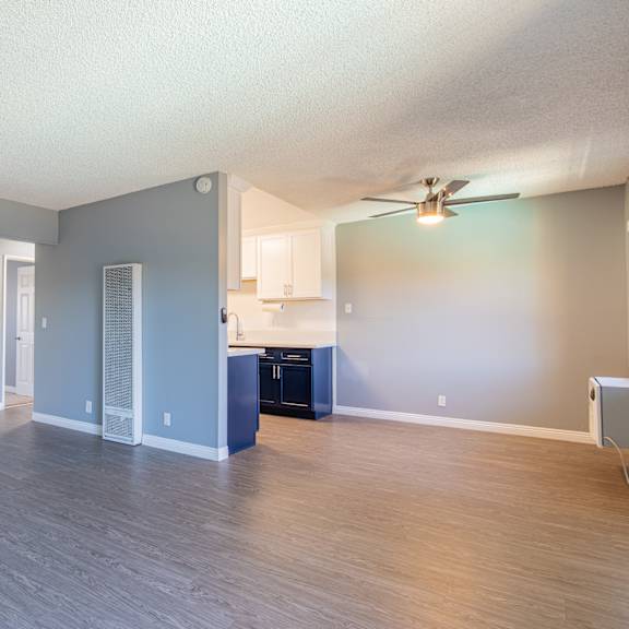 a spacious room with a ceiling fan and a kitchenette.