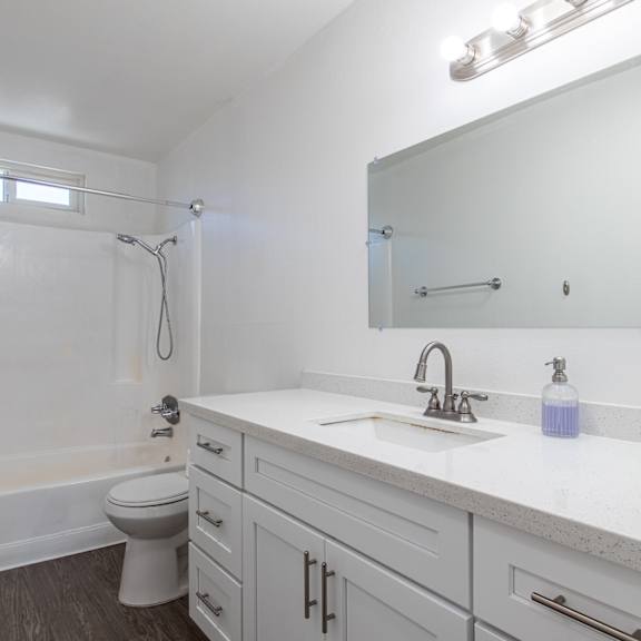 a white bathroom with a toilet, sink, and shower.