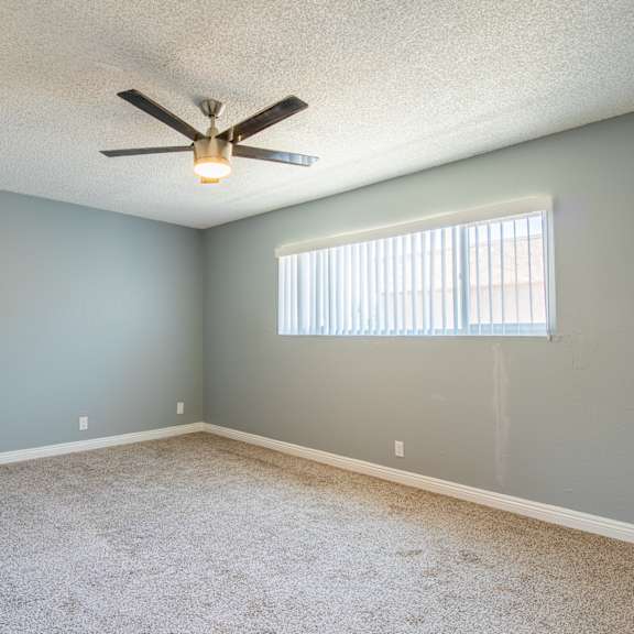 a room with a ceiling fan and a window with blinds.