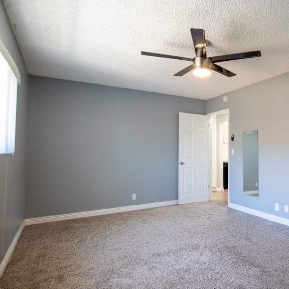 a room with a ceiling fan and carpeted floor.
