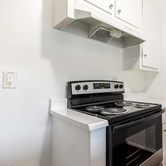 a white stove top oven with a black oven door sits on a white counter.