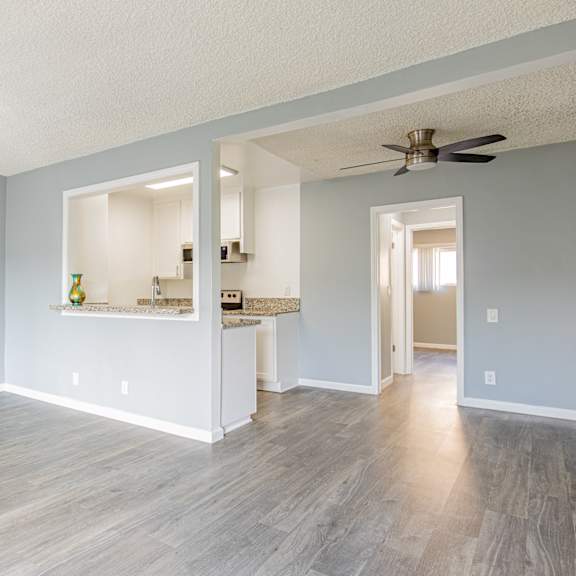 a room with a ceiling fan and a long wooden floor.