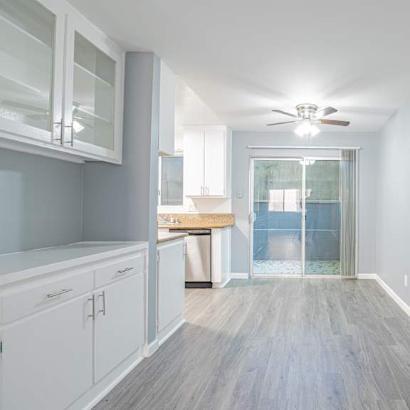 a long, narrow hallway with a ceiling fan and a door leading to a balcony.