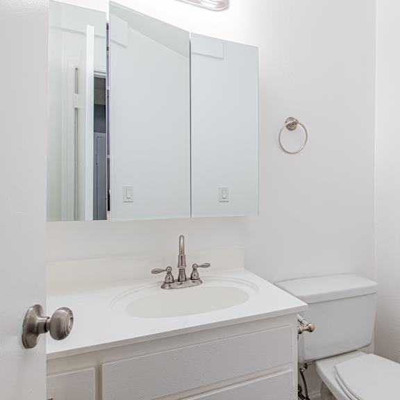 a white bathroom with a toilet, sink, and medicine cabinet.
