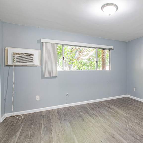 a room with a window and a wall-mounted air conditioning unit.