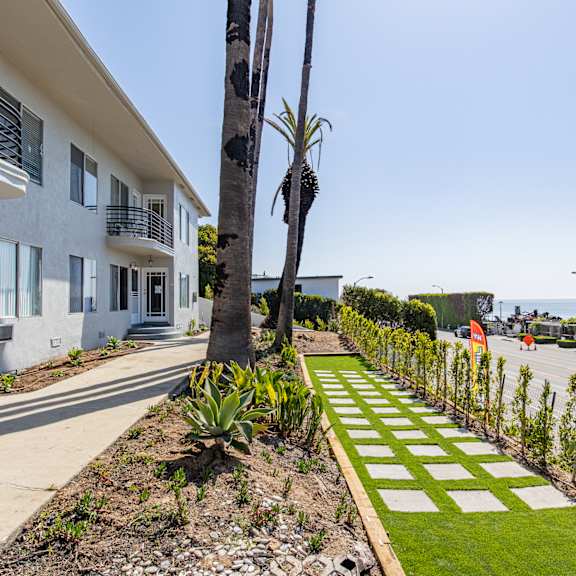 a white building with a balcony and a tree in front of it.