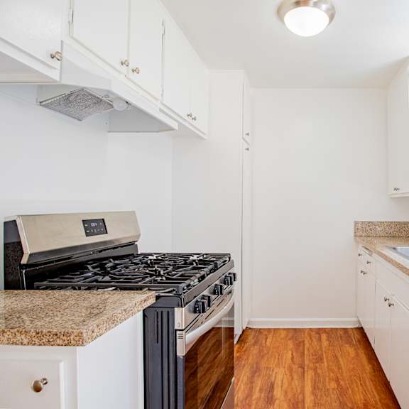 a kitchen with a black stove top oven and white cabinets.
