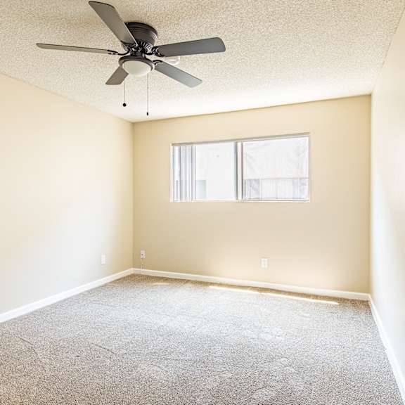 a room with a ceiling fan and a window.