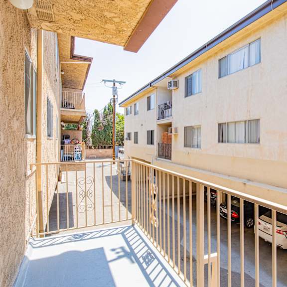 a view of a balcony with a metal railing and a car parked in the driveway.