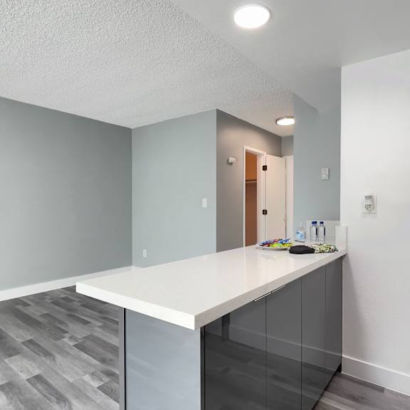 an empty kitchen with a white counter top and a door to a hallway