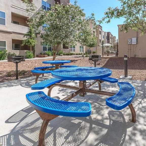 an outdoor picnic area with blue picnic tables and benches