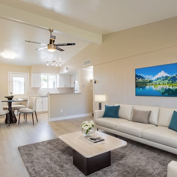 a living room with a white couch and a painting of a mountain scene on the wall.