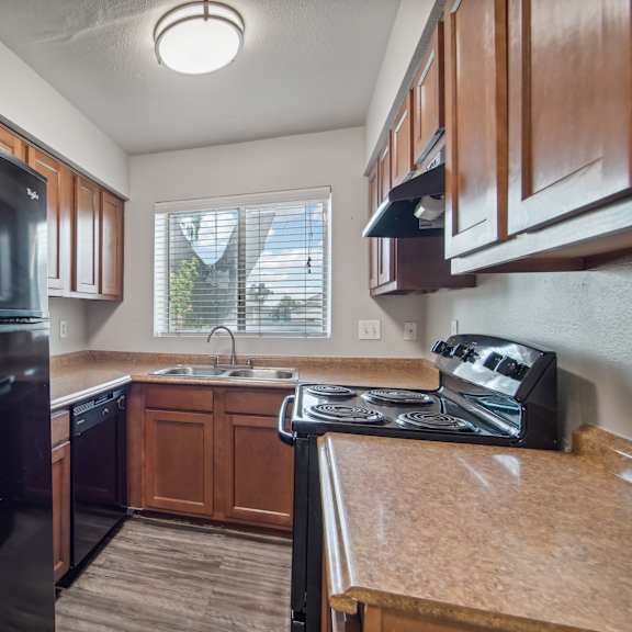 an updated kitchen with black appliances and wood cabinets