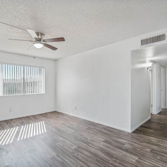 the living room of an empty apartment with a ceiling fan