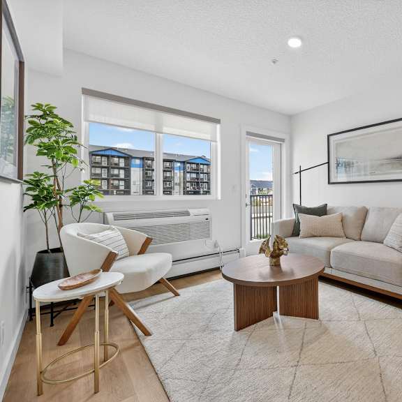 a living room with a white couch, a coffee table, and a large window.