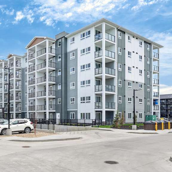 a large apartment complex with a parking lot in front.