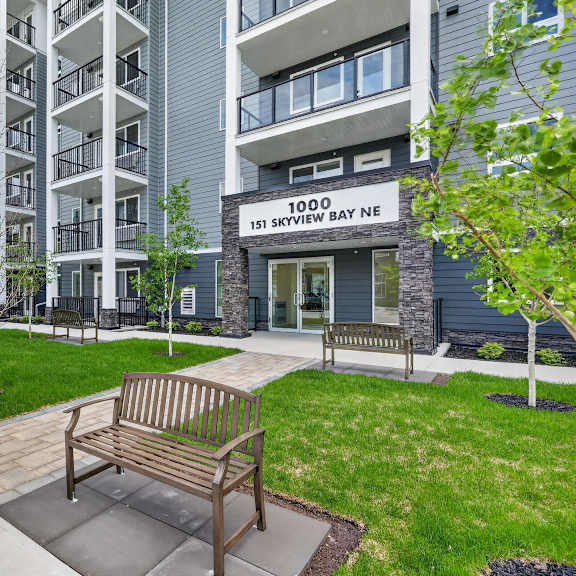a bench is situated on a concrete walkway in front of a building.