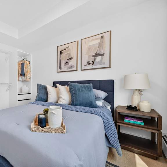 a bedroom with a bed, nightstand, and two pictures on the wall.