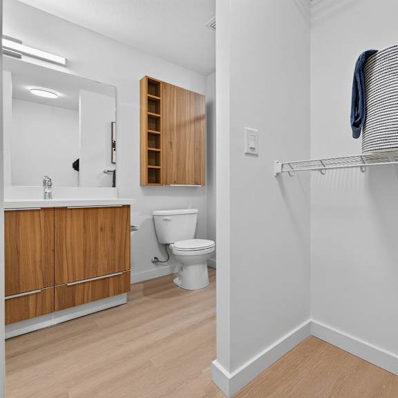 a white bathroom with a toilet and a shelf.