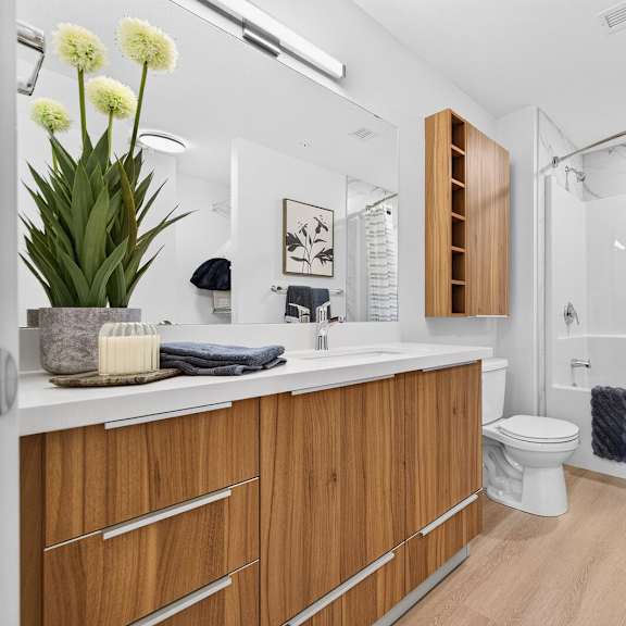 a bathroom with a white counter top and wooden drawers.