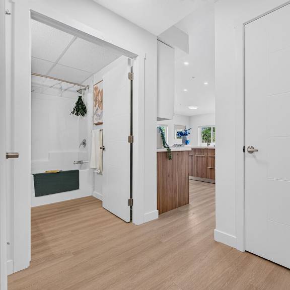 a white door is open to a kitchen.