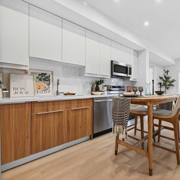 a modern kitchen with wooden chairs and a dining table.
