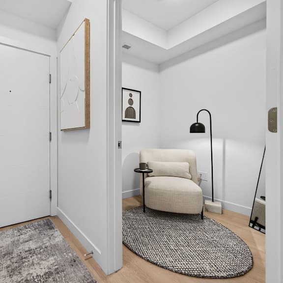 a white door with a silver handle is in a room with a grey rug and a white chair.