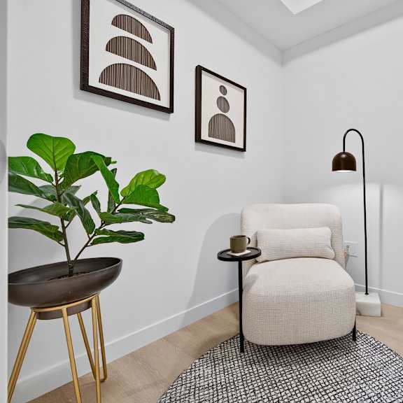 a living room with a chair, a plant, and a lamp.