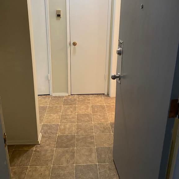 a hallway with three doors and tiled flooring.