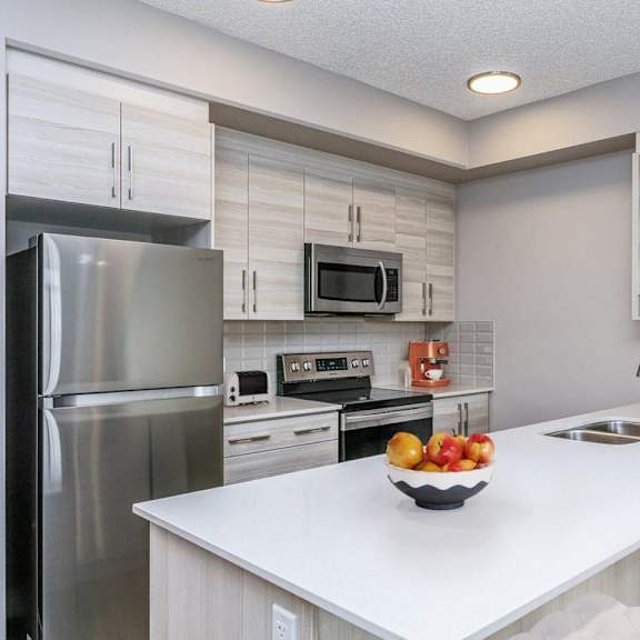 a modern kitchen with a white countertop and stainless steel appliances.