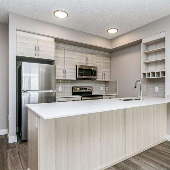 a modern kitchen with a refrigerator, microwave, oven, and sink.